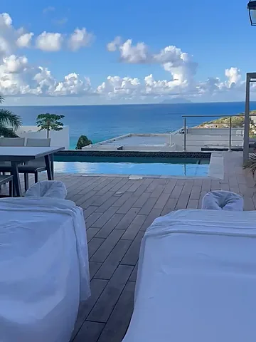 Two massage tables on a covered villa terrace overlooking an infinity pool and the ocean in St. Maarten