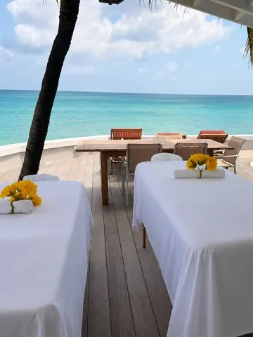 Massage tables with yellow roses set up on a beachfront deck for a group massage in St. Maarten