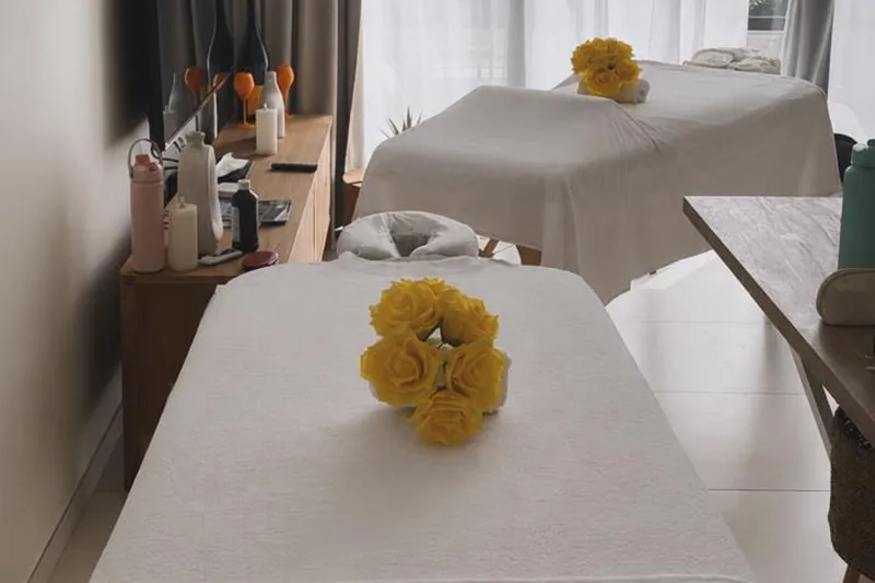 Indoor villa suite group massage setup in St Maarten Two massage tables styled with yellow roses side-by-side in a villa suite, set up for a group spa experience.
