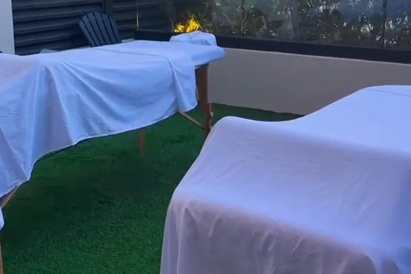 Outdoor rooftop terrace group massage setup in St Maarten Two massage tables set up on an outdoor rooftop terrace at dusk for a group wellness session in St Maarten.