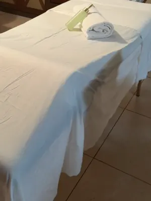 Massage table with a rolled towel and massage oil set up in a hotel room in St. Maarten