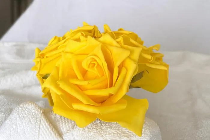 Close-up of a yellow rose and rolled towel styled on a massage table, representing the calming Swedish massage experience in St Maarten.