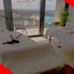 Fourteen in MulletBay with two massage tables near large windows, offering a stunning ocean view. A serene atmosphere is enhanced by soft lighting and view of mullet bay beach