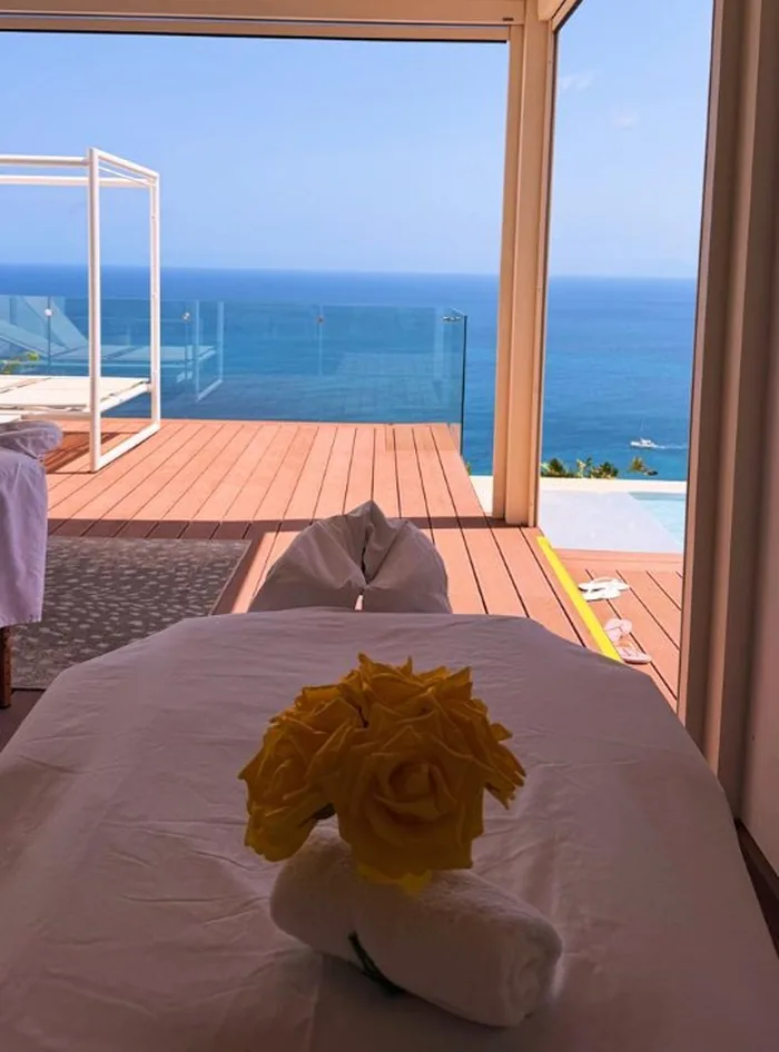 Massage table styled with a yellow rose and rolled towel on an open-air villa veranda overlooking the ocean in St Maarten